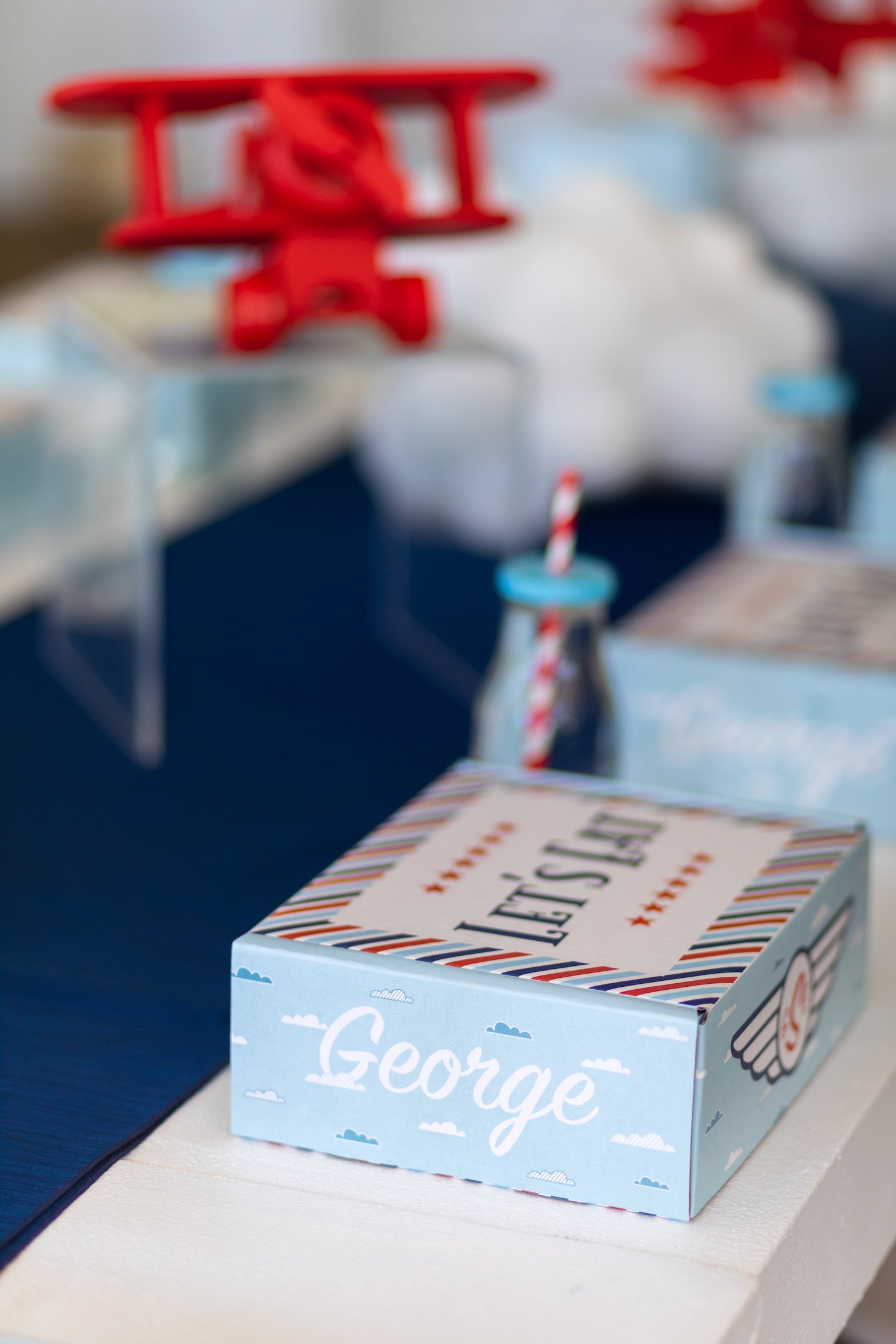 Red, white, and blue airplane birthday party featuring aviation-themed decor, custom lunch boxes, and playful details for a two- and four-year-old celebration.