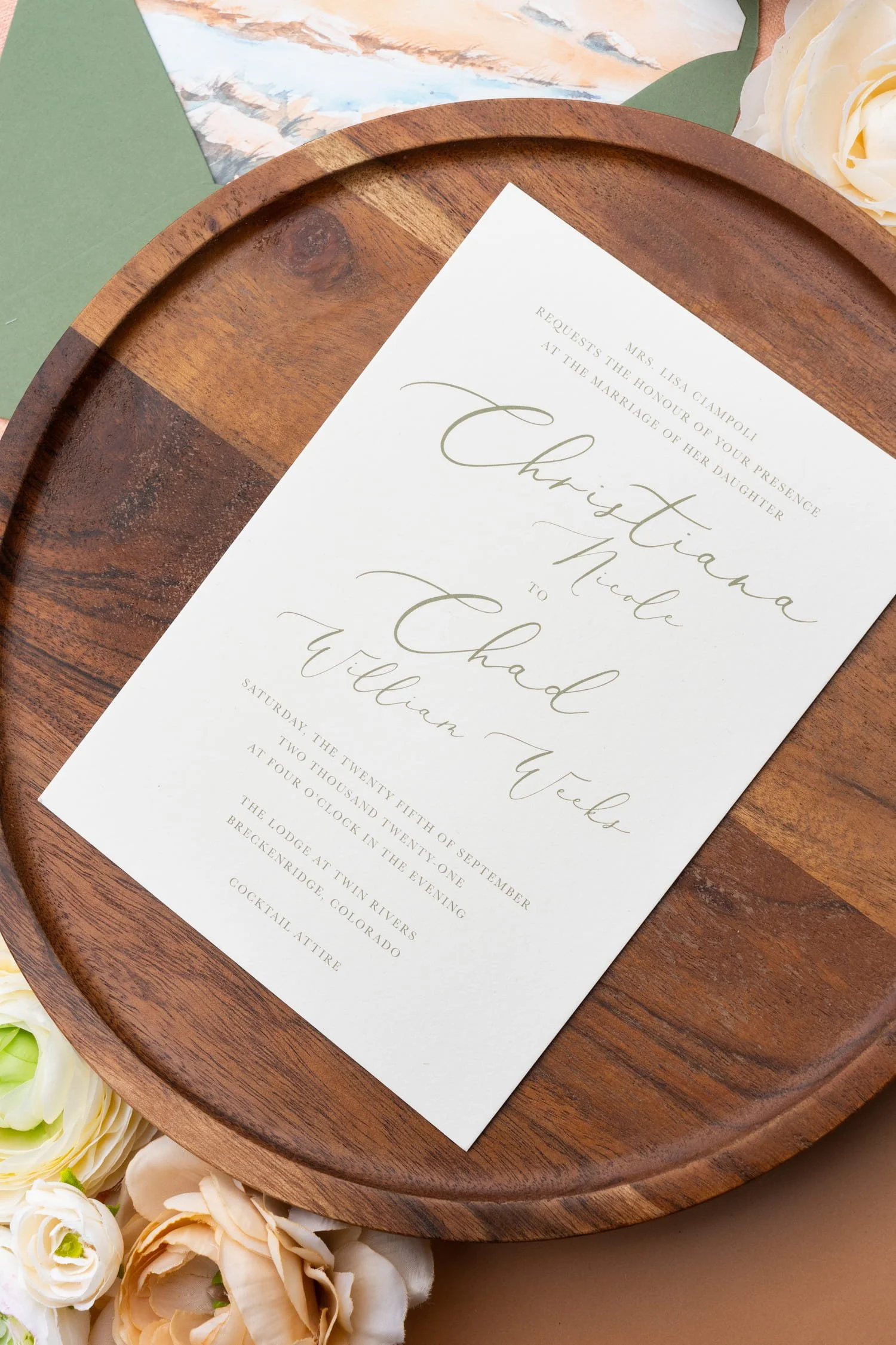 Close-up of a mountain-inspired wedding invitation with watercolor fall landscapes, modern calligraphy, and a soft peach and sage color palette inspired by luxury ranch weddings.