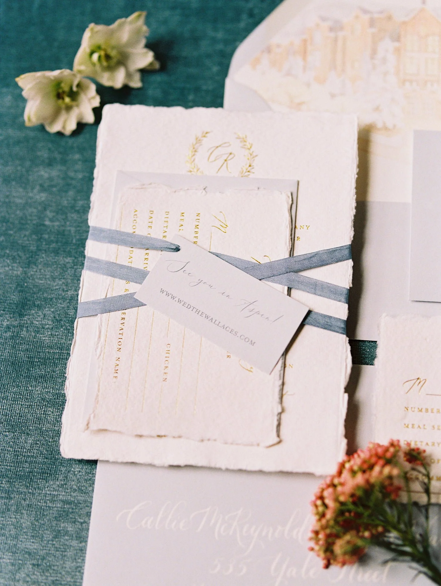 Luxury winter wedding invitation suite styled with handmade cotton paper, gold foil printing, silk ribbon, winter botanical stamps, and a custom watercolor envelope liner inspired by Aspen.