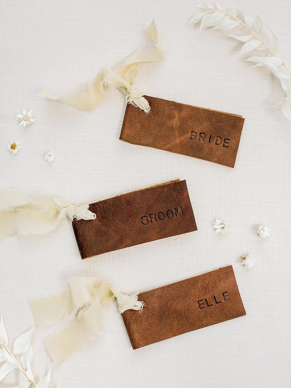 Wedding parasols finished with hand-stamped leather tags and hand-dyed silk ribbon for an outdoor celebration at Boulder Flower Farm.
