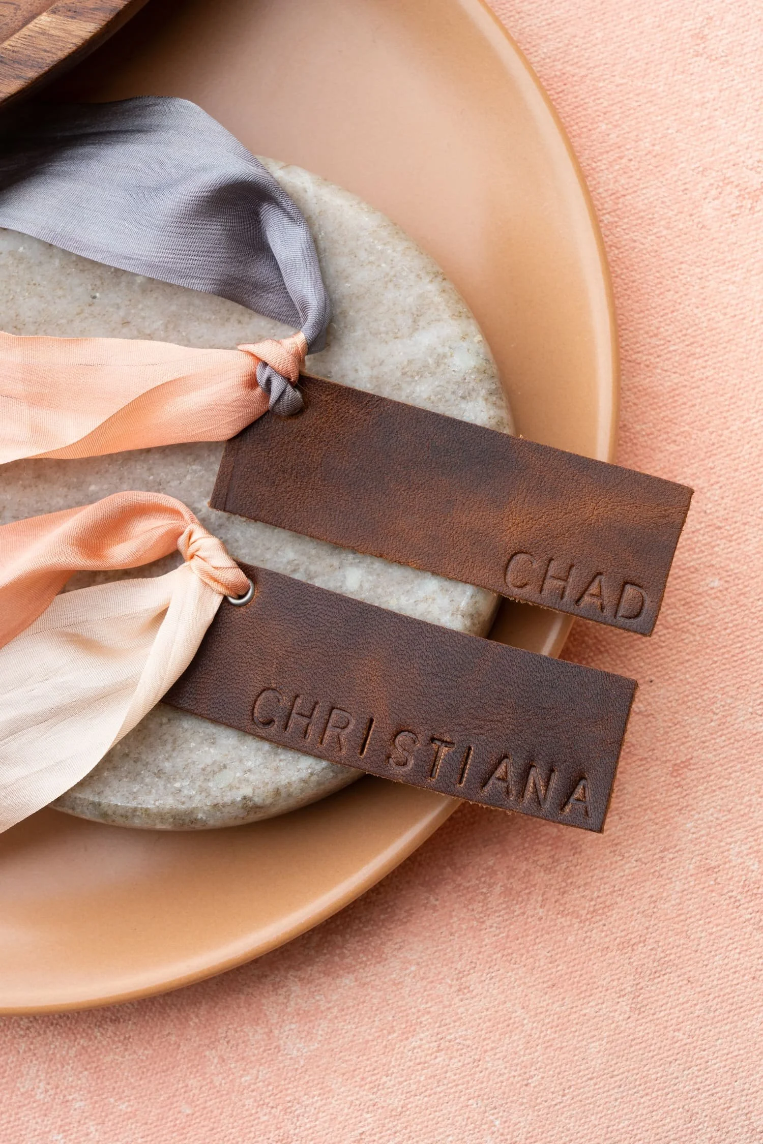 Hand-stamped leather place cards displaying guest names, adding handcrafted Western charm to an elevated mountain wedding tablescape.