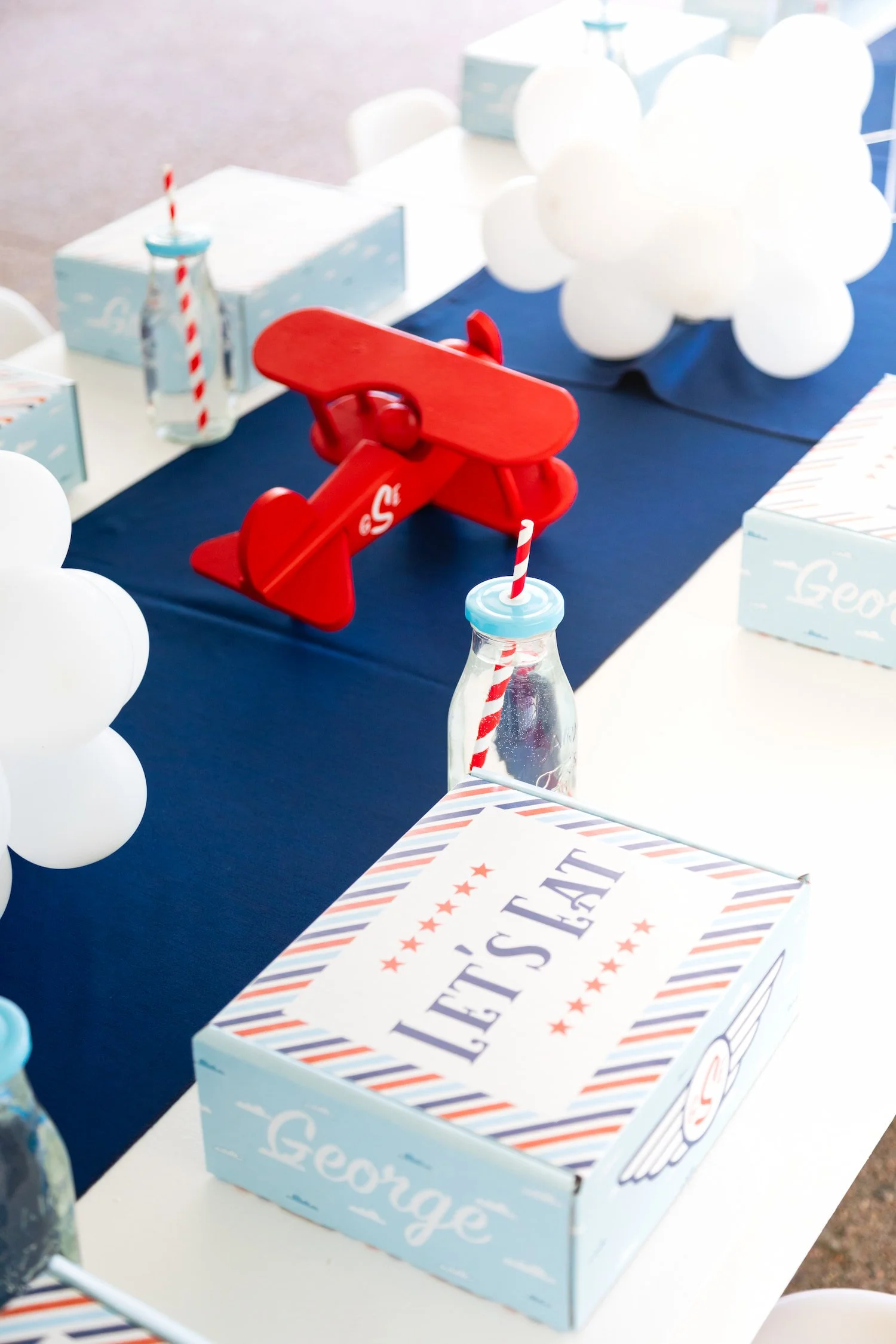 Red, white, and blue airplane birthday party featuring aviation-themed decor, custom lunch boxes, and playful details for a two- and four-year-old celebration.