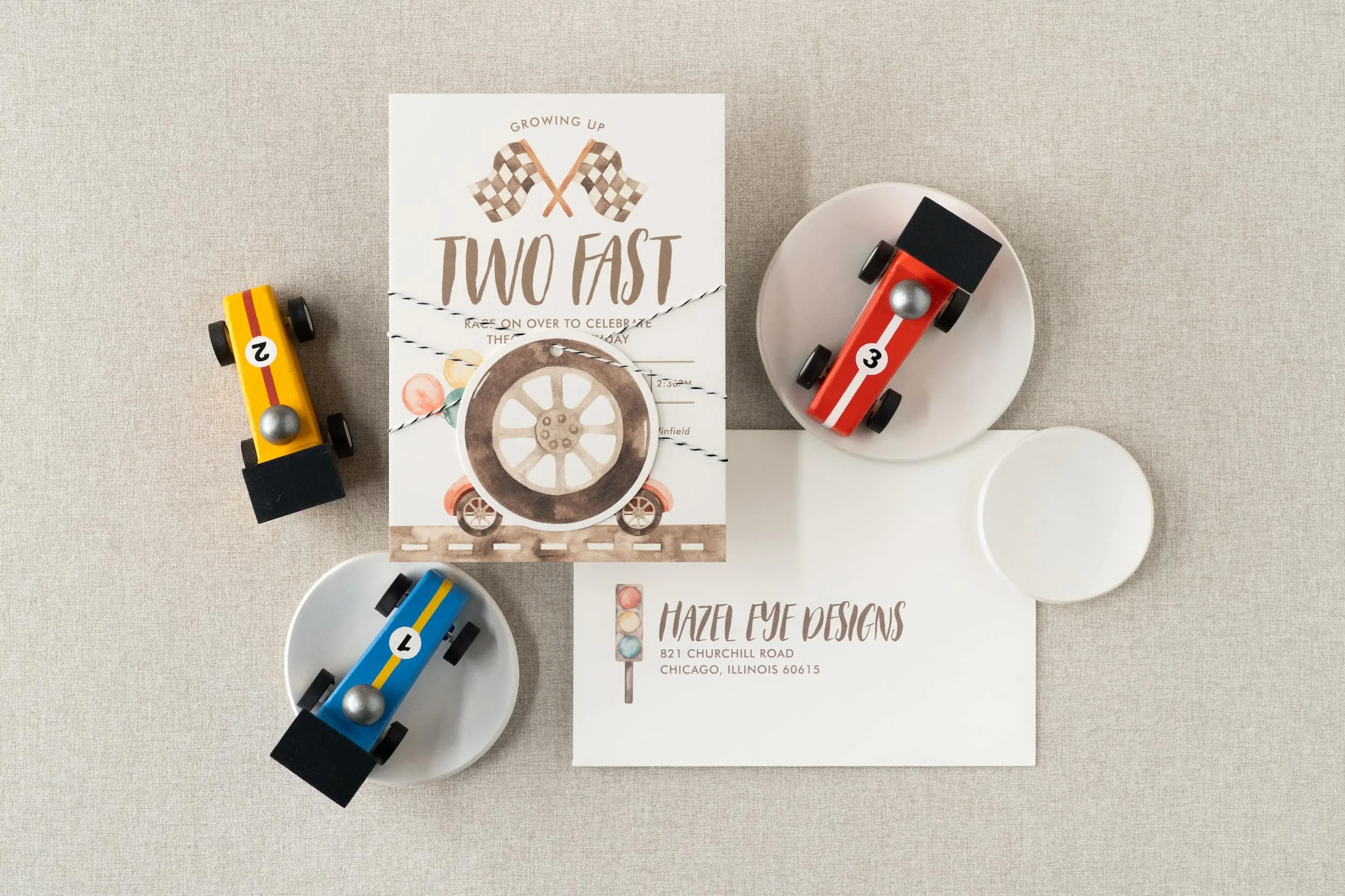 “Two Fast” race car birthday invitation suite for a two-year-old boy featuring watercolor race car illustrations, black-and-white check details, and vintage-inspired racing stamps.
