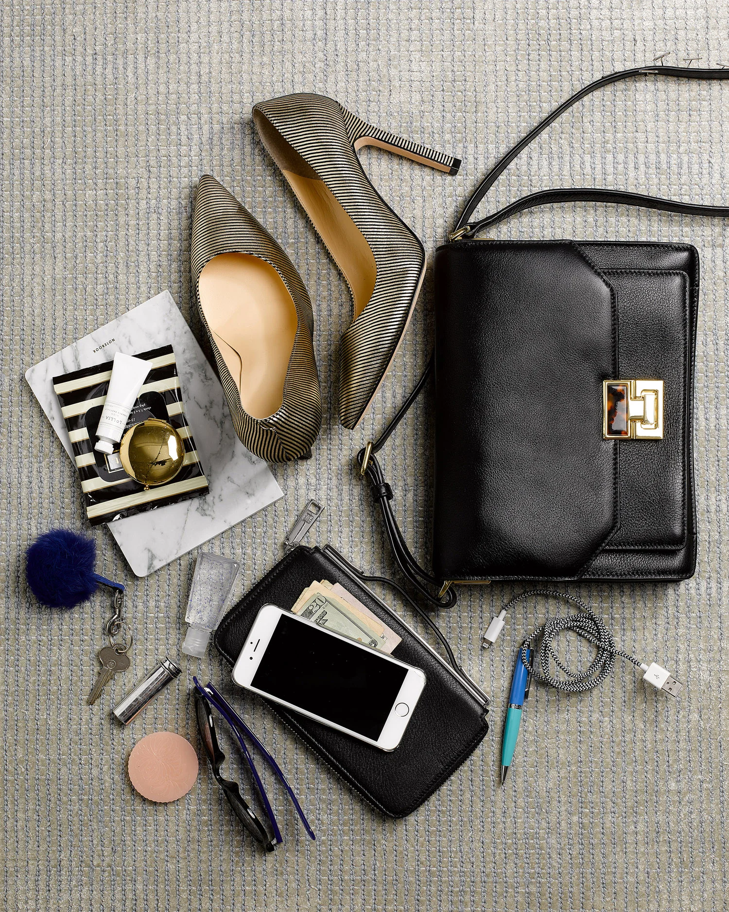 bag spill still life of a woman's things with heels, her notebook, fluffy key chain,