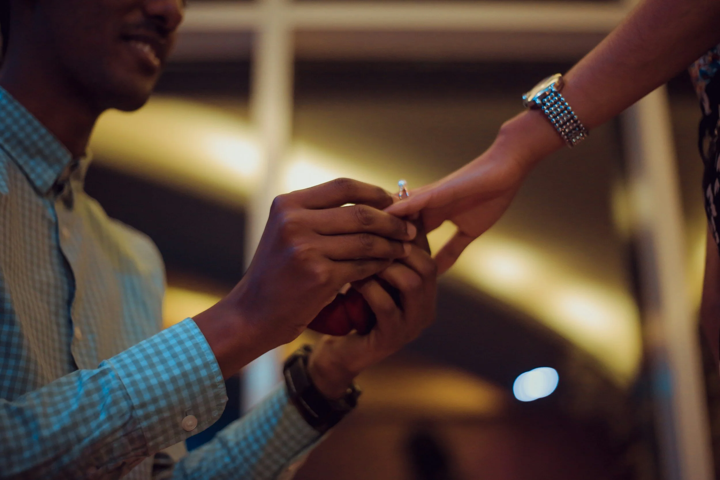 BIPOC newly engaged couple with man placing ring on woman's finger