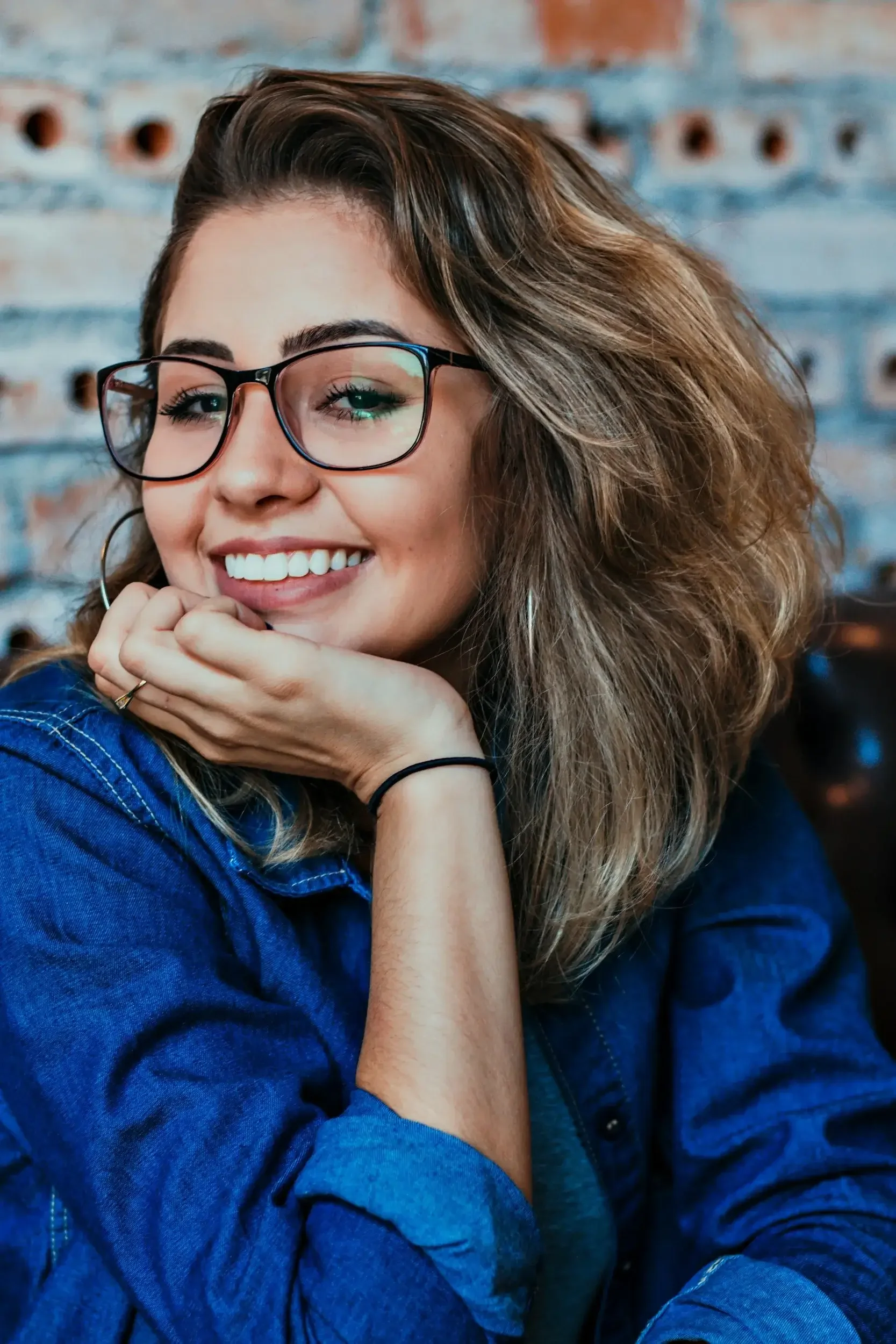 latina woman smiling with hand to her chin after completing therapy and feeling more content, kindman & co. therapy 90042
