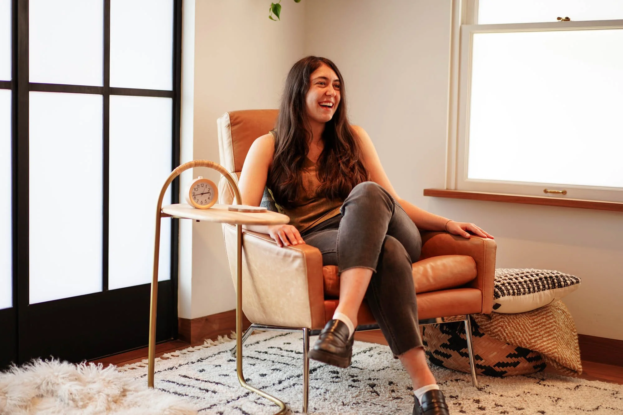 Sarah Barukh, ACSW laughing in chair at Kindman & Co. Therapy in Highland Park