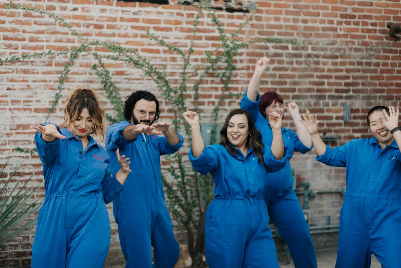 Part of Kindman & Co. team dancing and being silly in matching jumpsuits