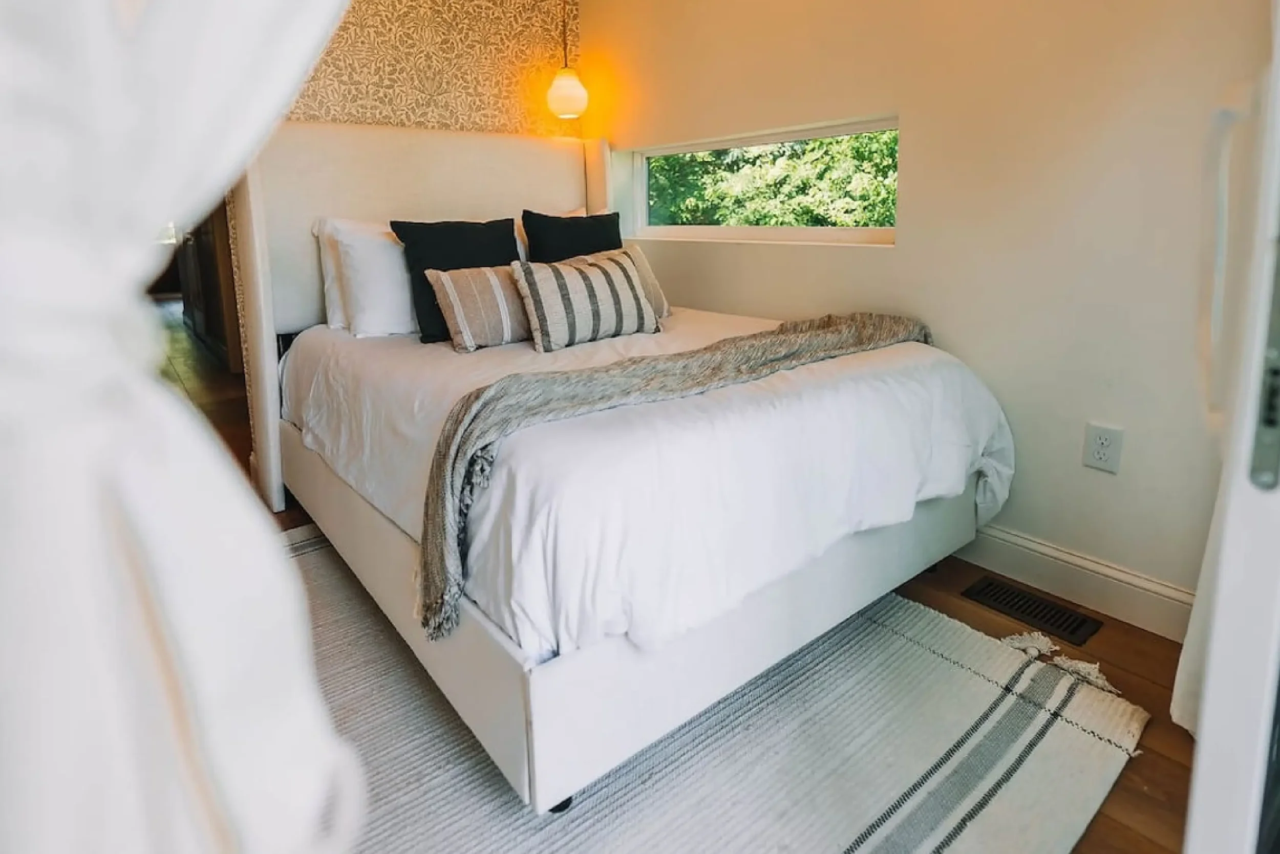 Cozy queen bedroom with white linens and a forest-view window at The Overlook cabin