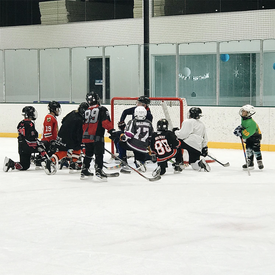 class of junior ice hockey students receiving coaching instructions