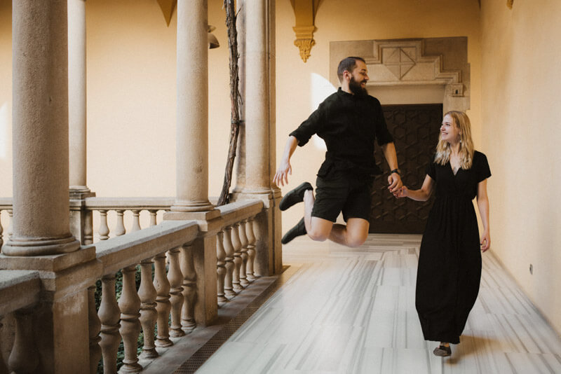 Young couple jumping old Gothic architecture