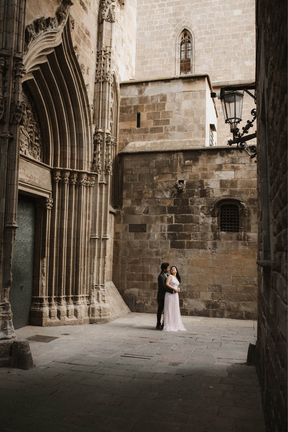 Couple behind the Gothic Cathedral Barcelona in wedding dress white