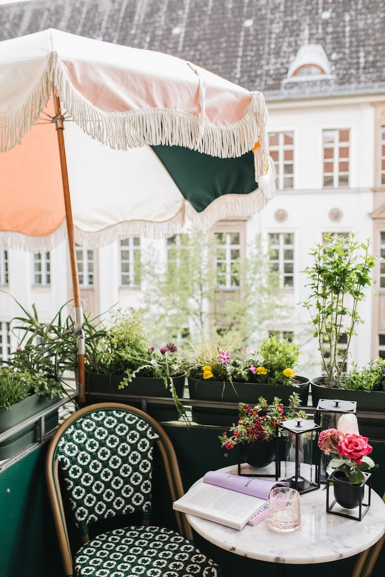    a colourful bright apartment in berlin, gallery wall, artworks, pink kitchen, terrazzo worktops, terrazzo, striped bedclothes, bedroom, striped curtains, seating area, curtains, stipes, yellow sofa, living room, large living room windows, balcony 