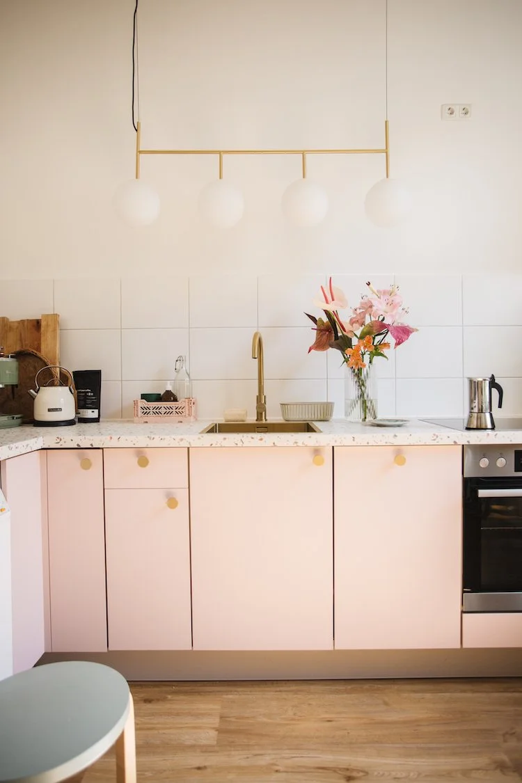    a colourful bright apartment in berlin, gallery wall, artworks, pink kitchen, terrazzo worktops, terrazzo, striped bedclothes, bedroom, striped curtains, seating area, curtains, stipes, yellow sofa, living room, large living room windows, balcony 