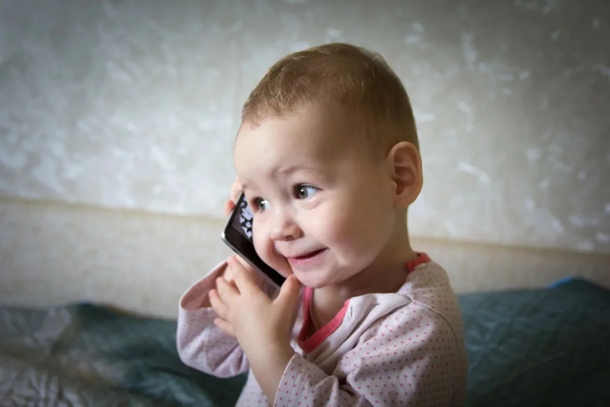 Smiling toddler holding a phone to her ear - contact Embryo Connections to start your embryo donation journey