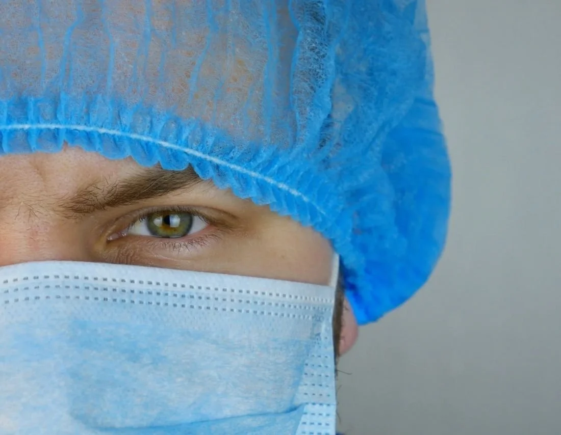 Fertility clinic provider in a blue surgical cap and mask, part of the care team supporting embryo donation for intended parents