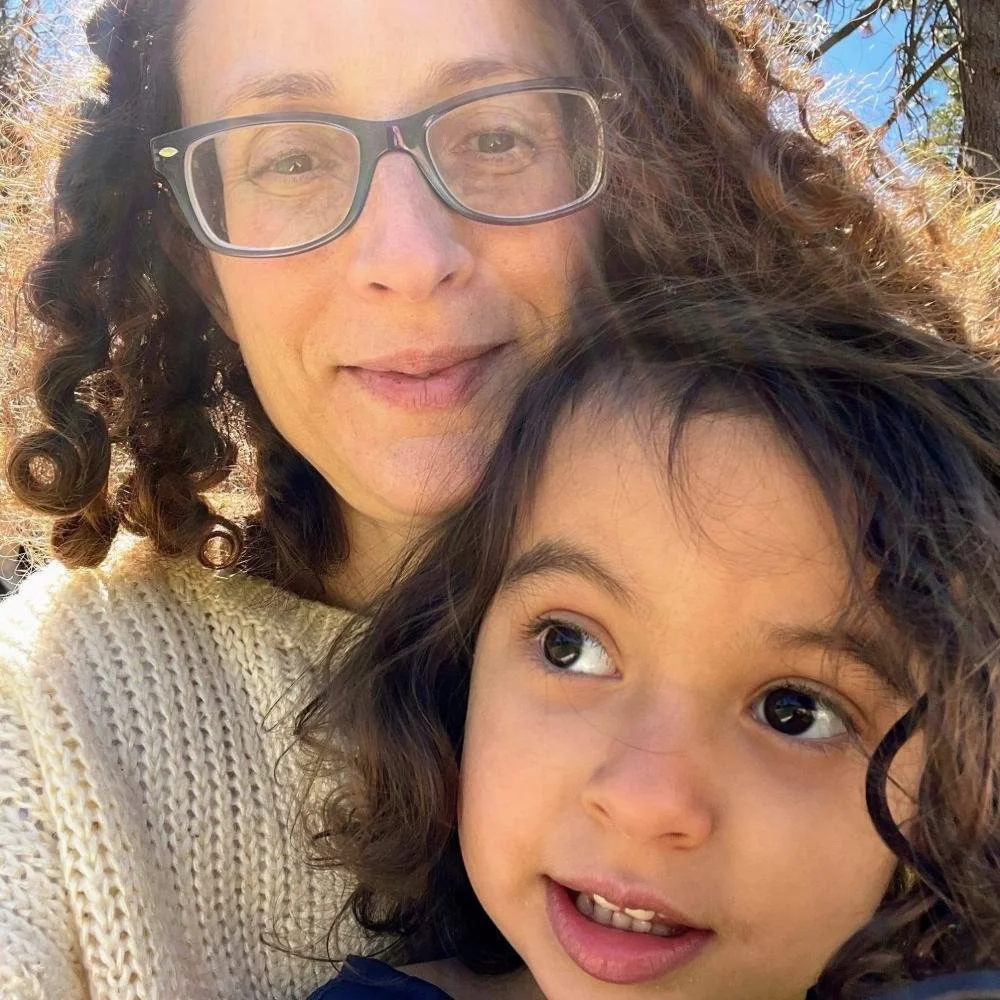 Mother smiling outdoors with her young daughter, conceived through embryo donation