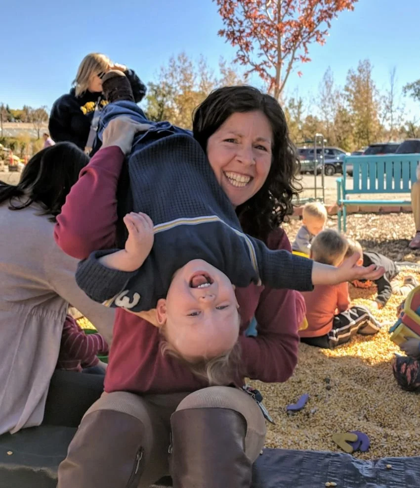 Embryo donor mom laughing with her child at a playground on an autumn day
