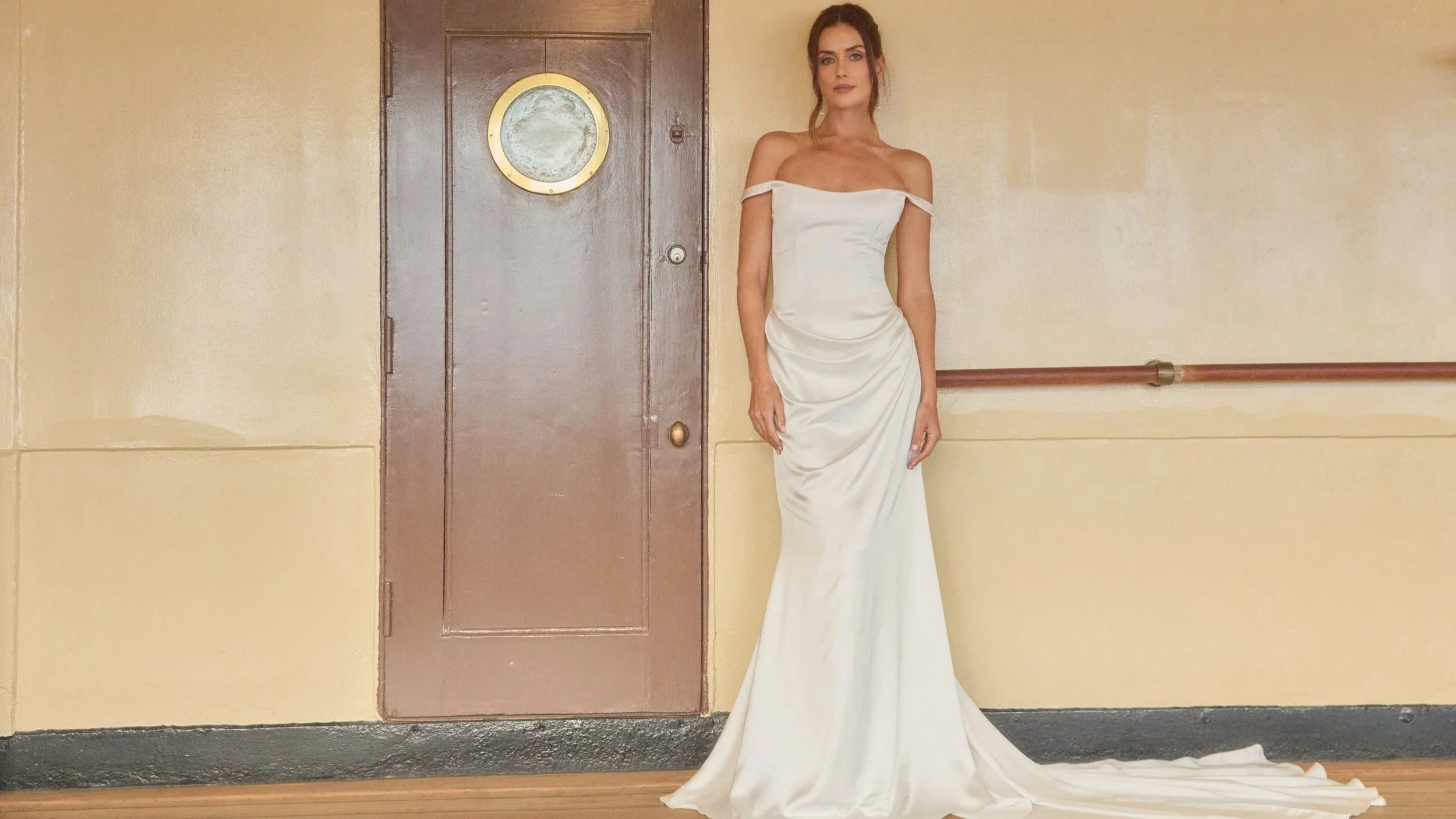 Model wearing the Bronte wedding dress by Tara Lauren, a sleek off-the-shoulder satin gown available at Heart Aflutter Bridal in London