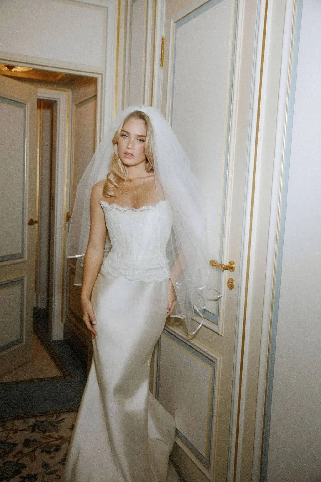 Sarah Seven Sarah wedding dress featuring a fitted satin column skirt, lace corset bodice with eyelash trim, and a soft cathedral veil, available at Heart Aflutter Bridal in London.