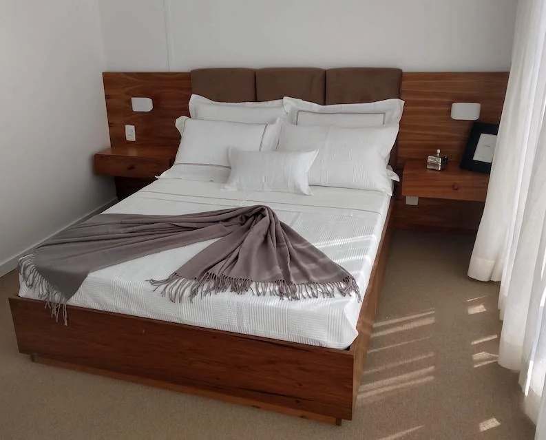 Cama da suíte com cabeceira e apoios laterais