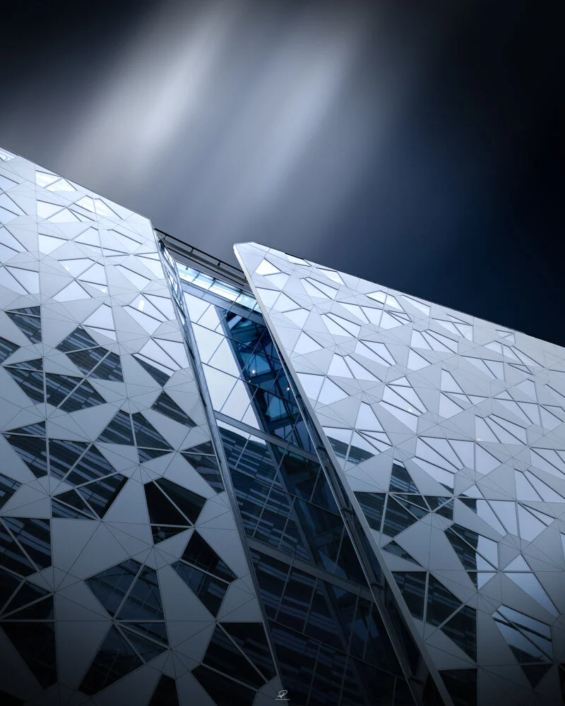 Modern glass building with geometric facade under a cloudy dark sky. Arkitektur foto Oslo.