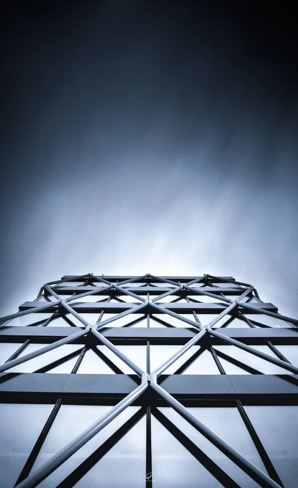Low-angle view of a modern building with a geometric metal framework against a cloudy sky. Arkitektur foto Oslo. Fornebu.