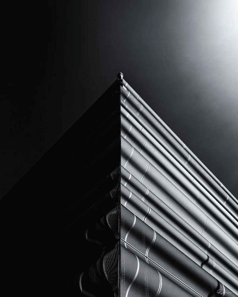 Close-up of a modern building's corner with metal and glass facade, illuminated by sunlight. Arkitektur foto Oslo.