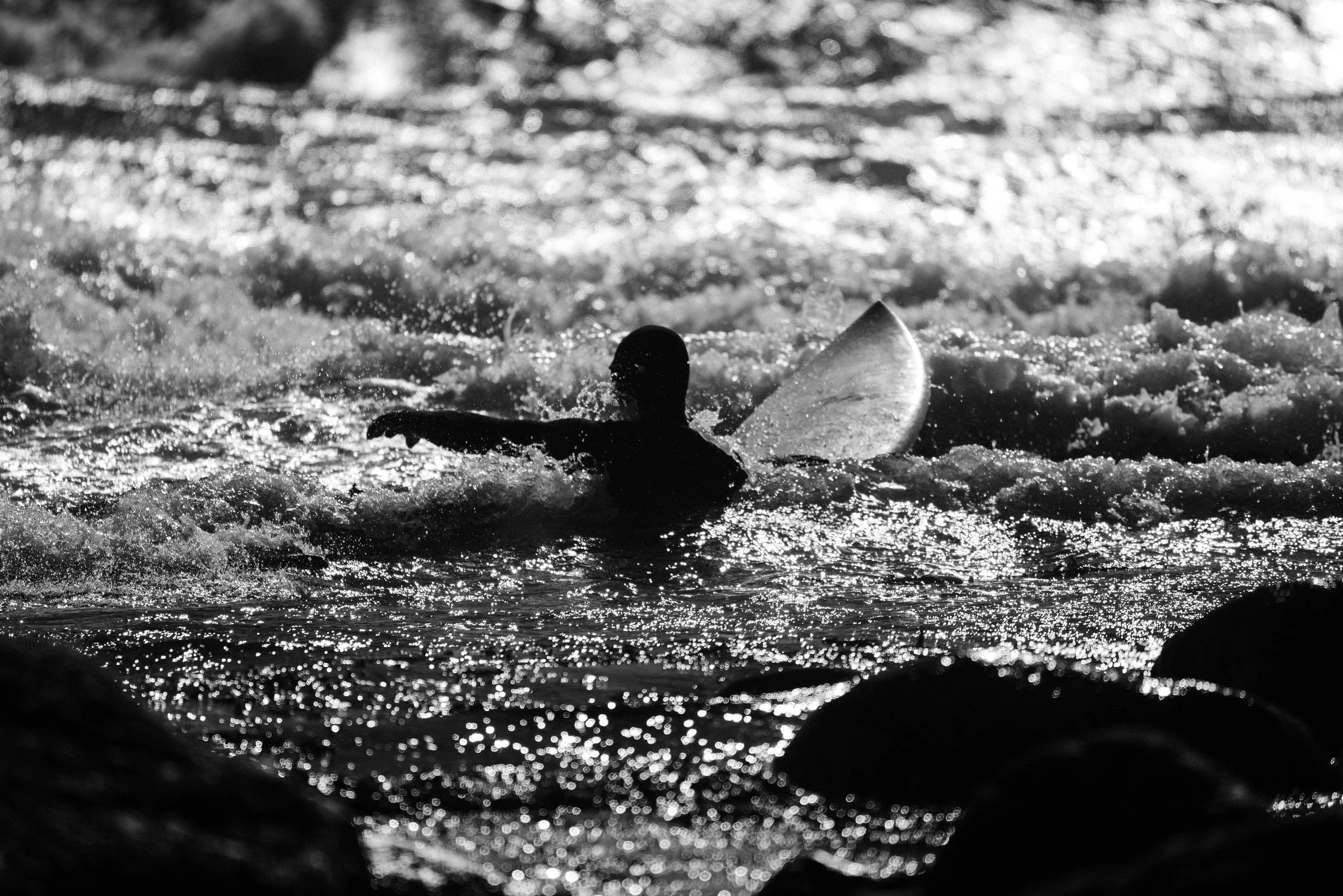 Minimalist black and white photograph of a surfer watching waves at Saltstein beach in Norway. Capturing atmosphere, movement, and solitude in coastal landscape photography.
