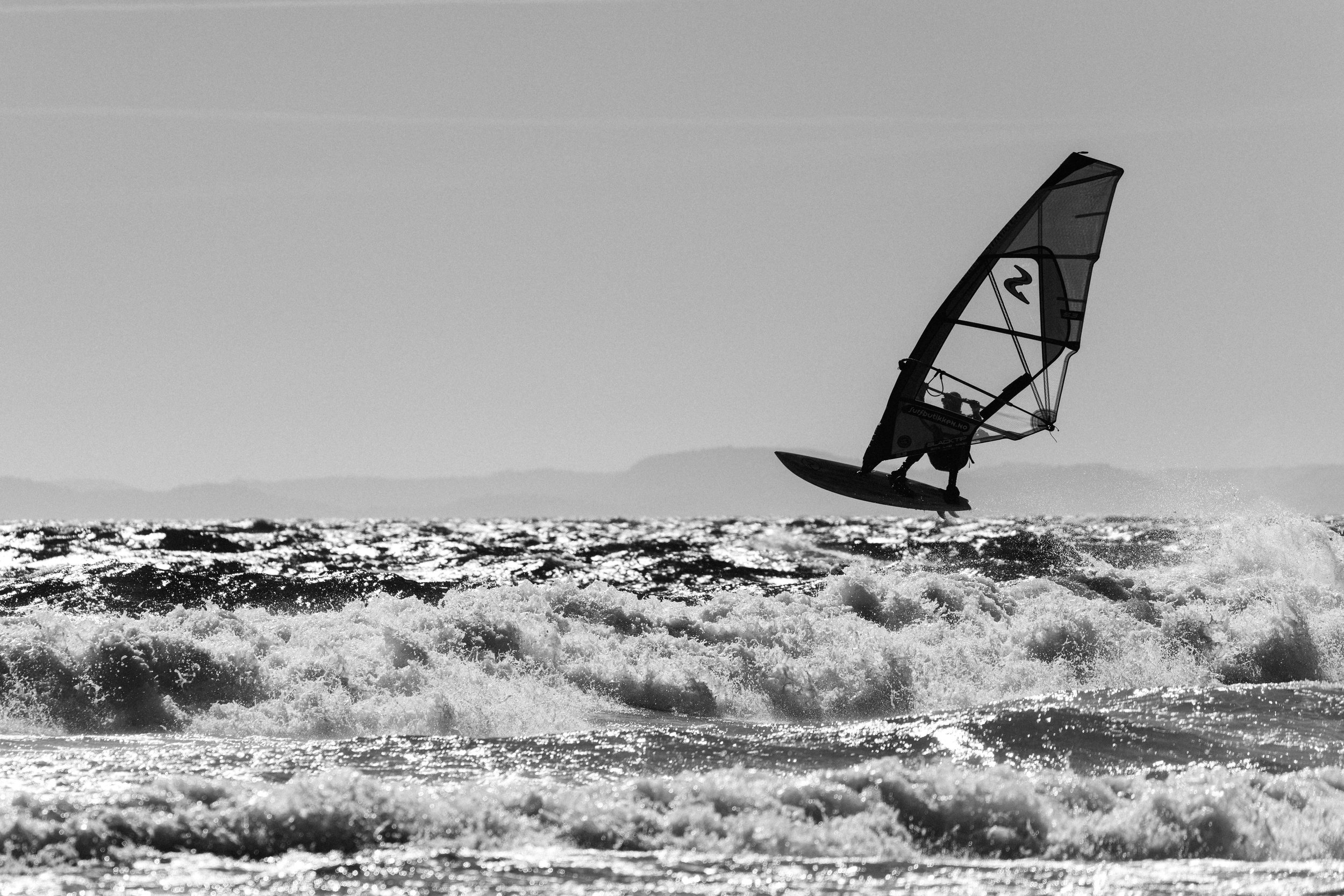 Dynamic windsurfing captured in strong coastal waves at Saltstein beach. A powerful moment of balance, motion, and energy in Scandinavian surf conditions.