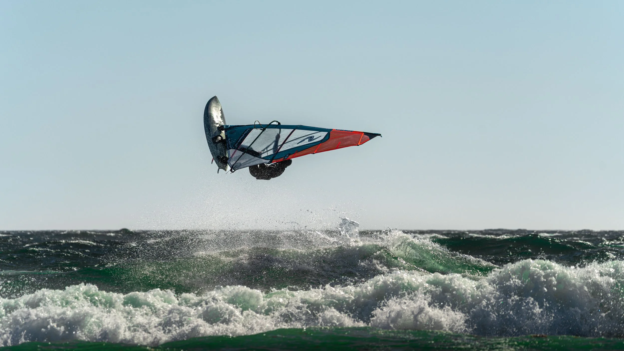 Dynamic windsurfing captured in strong coastal waves at Saltstein beach. A powerful moment of balance, motion, and energy in Scandinavian surf conditions.