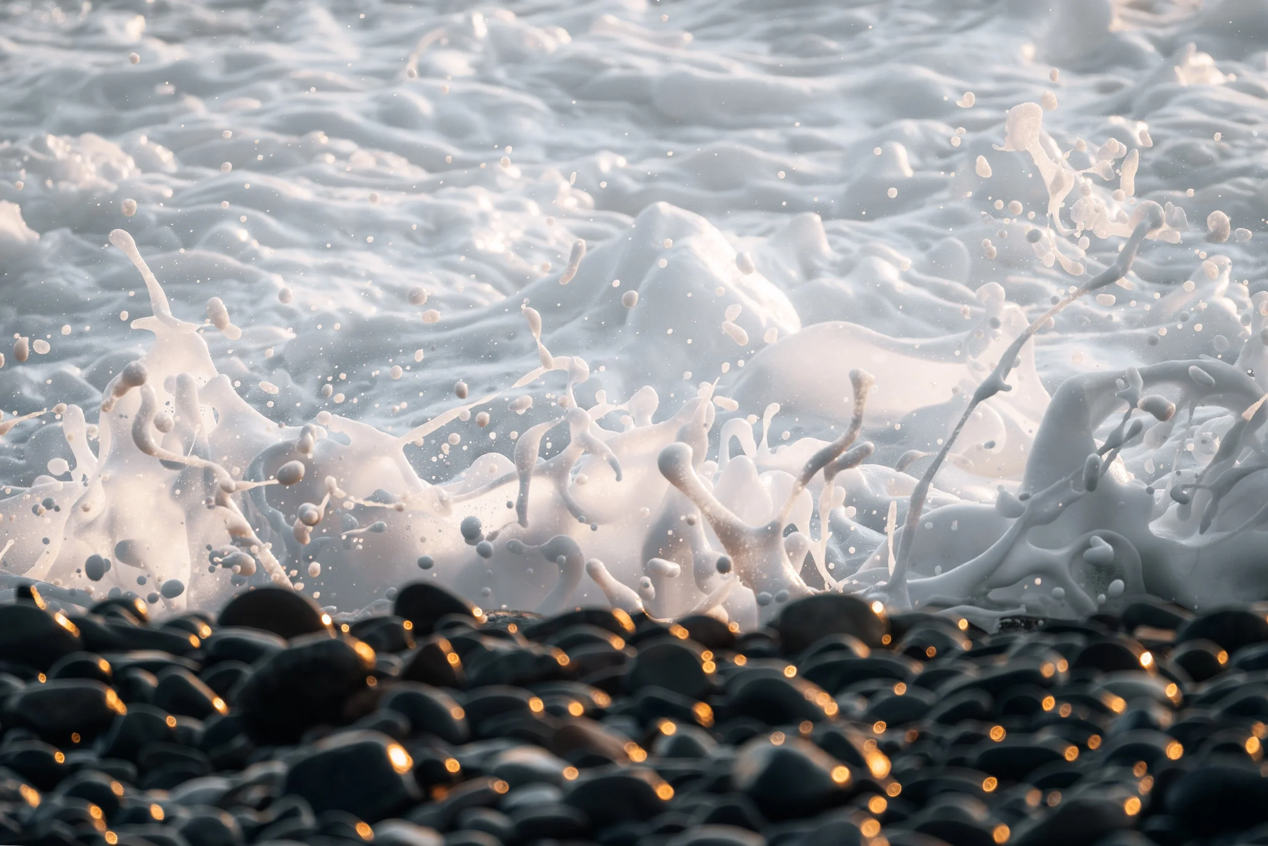 Waves crashing onto a pebbly beach with foam and spray