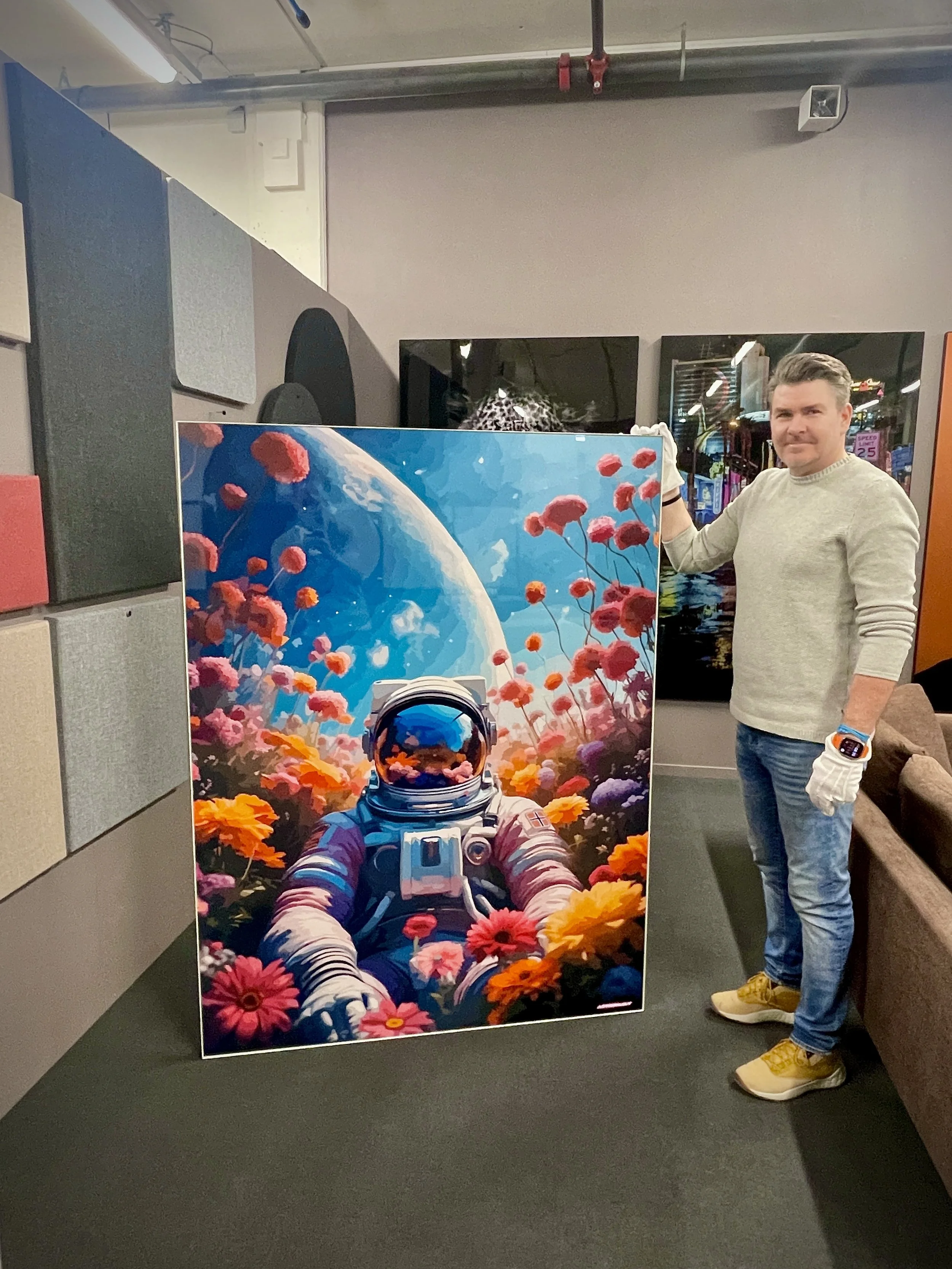 A man standing next to a colorful artwork of an astronaut floating among flowers with Earth visible in the background.