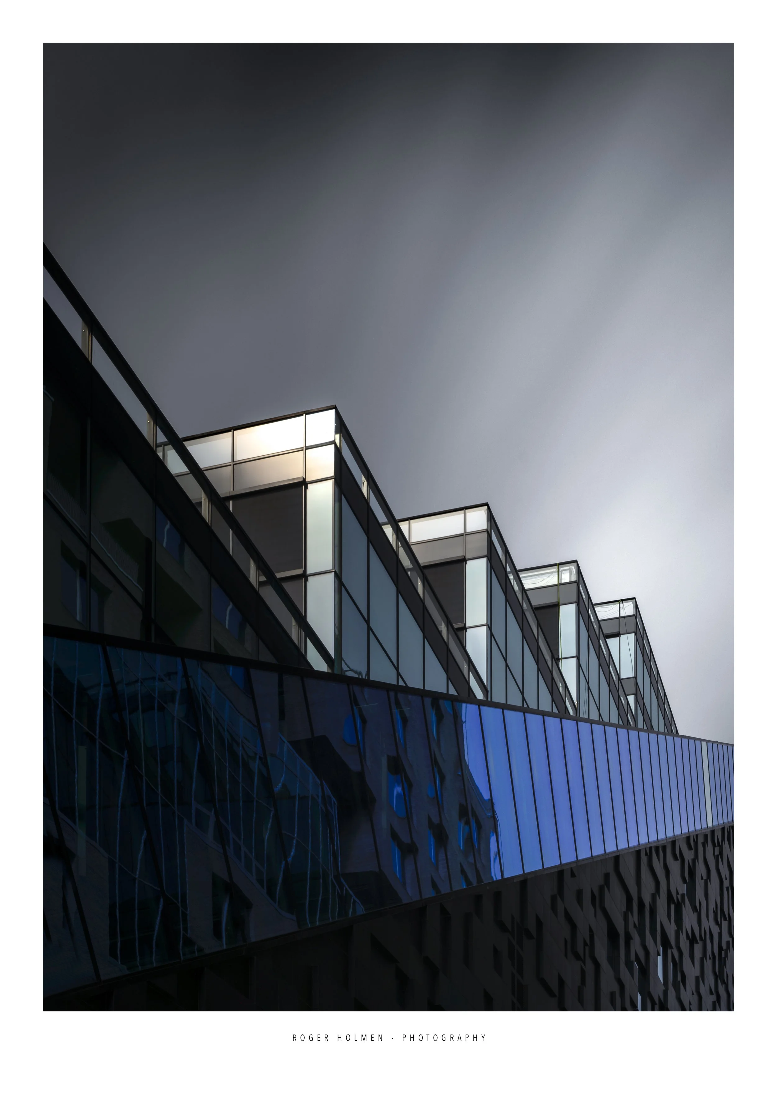 Modern glass building with geometric architecture against a dark sky.