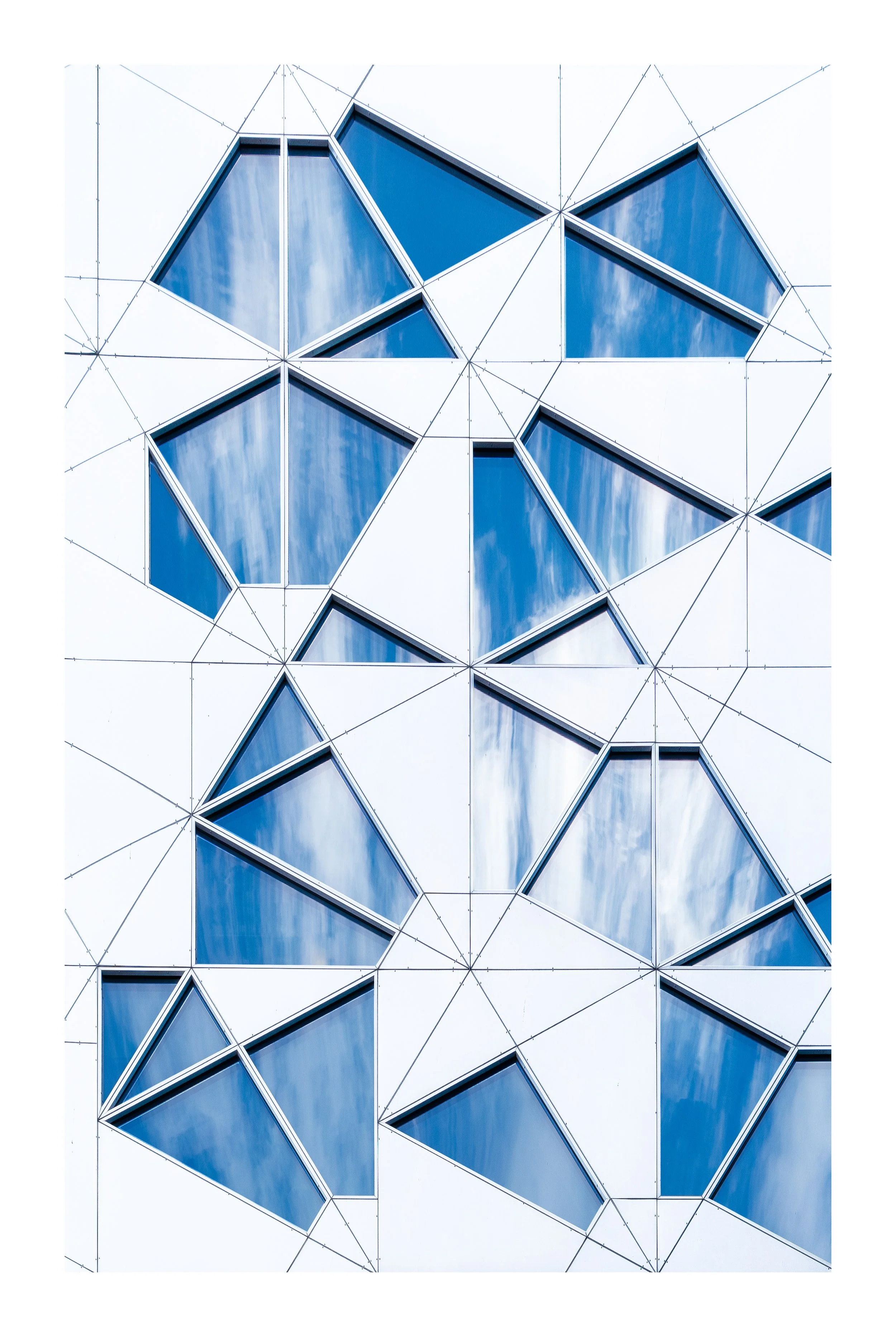 Close-up of a modern building facade with geometric patterns, featuring blue-tinted glass windows and metallic frames. Barcode Oslo. Arkitektur foto.