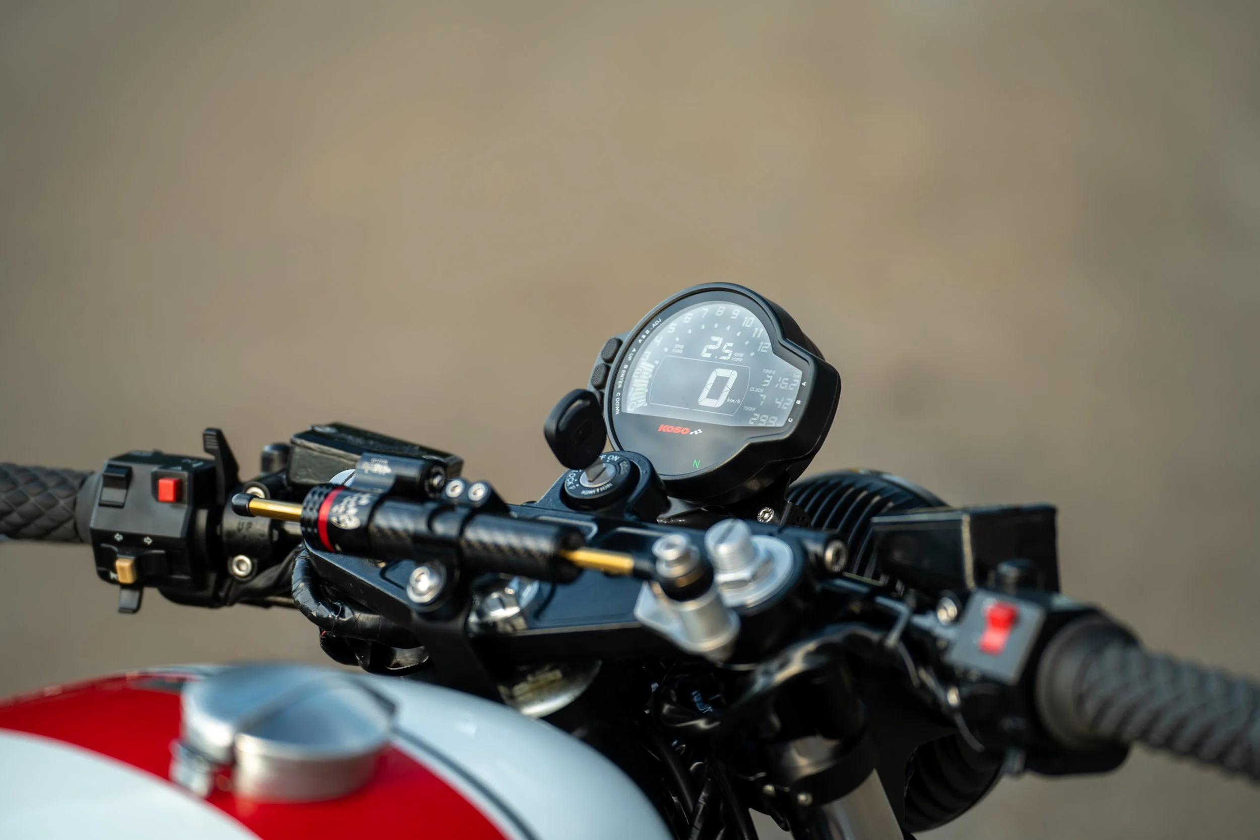 Close-up of a digital motorcycle dashboard showing speed, gear, and other metrics, with handlebars and grips visible in the foreground.
