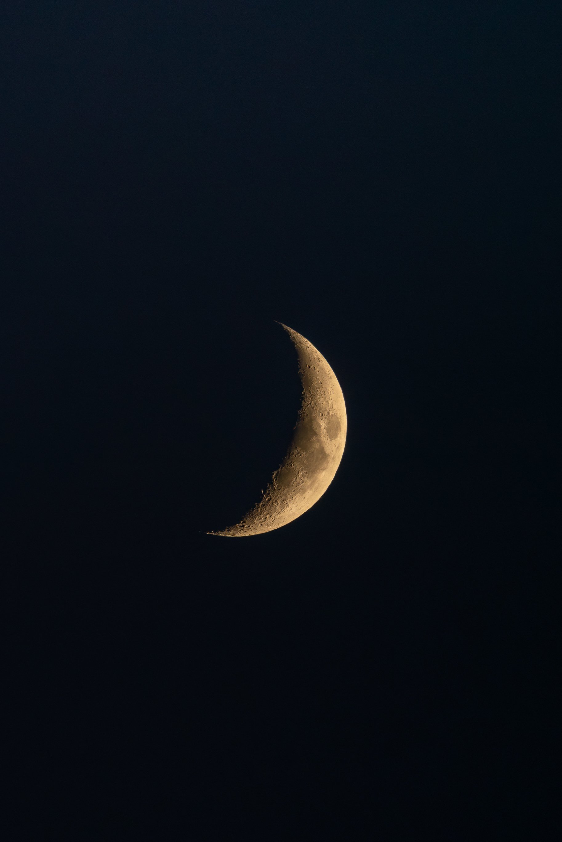 A close-up photograph of the moon showing its crescent phase against a dark sky.