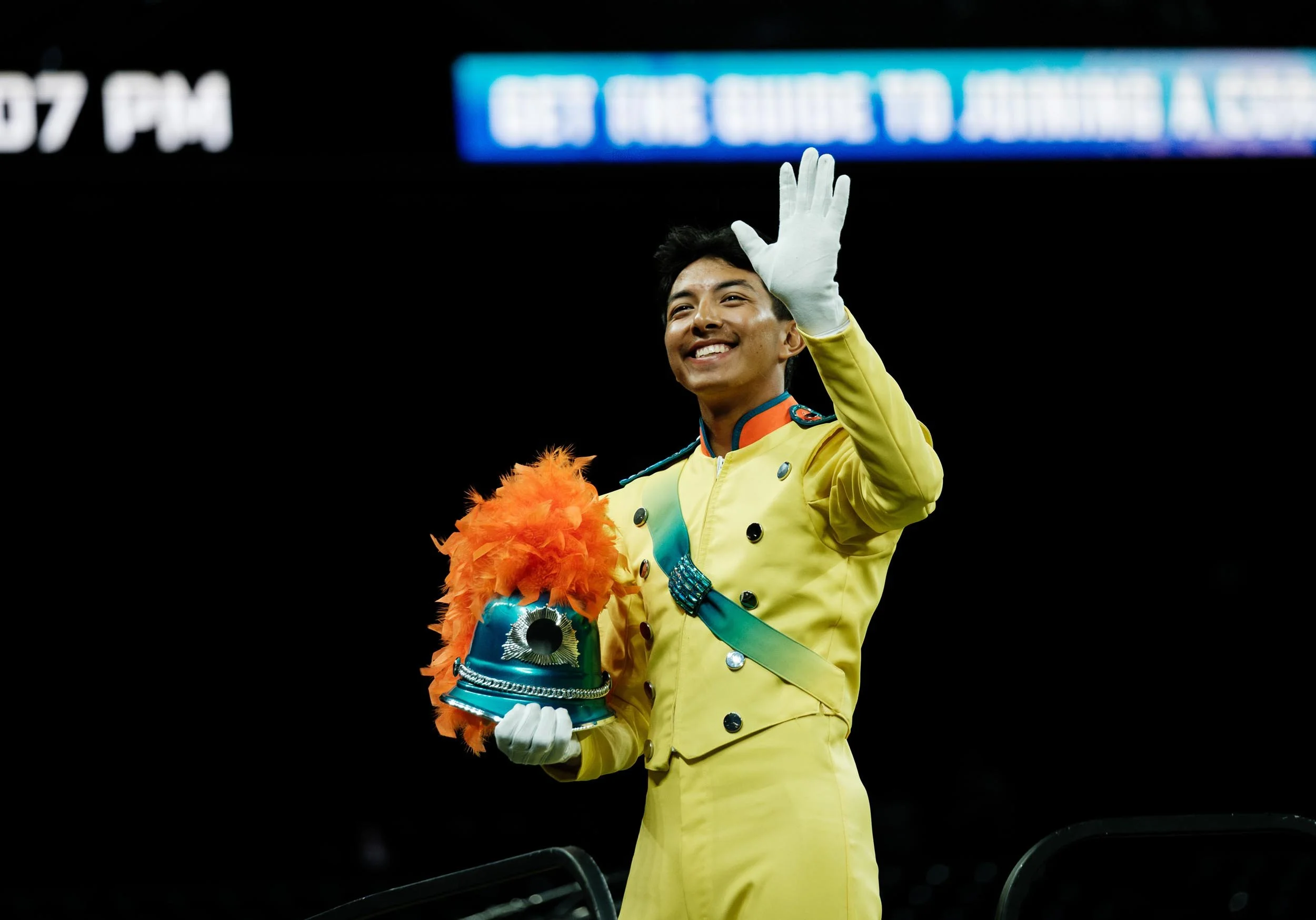 Photo of Bluecoats drum major waving and smiling.