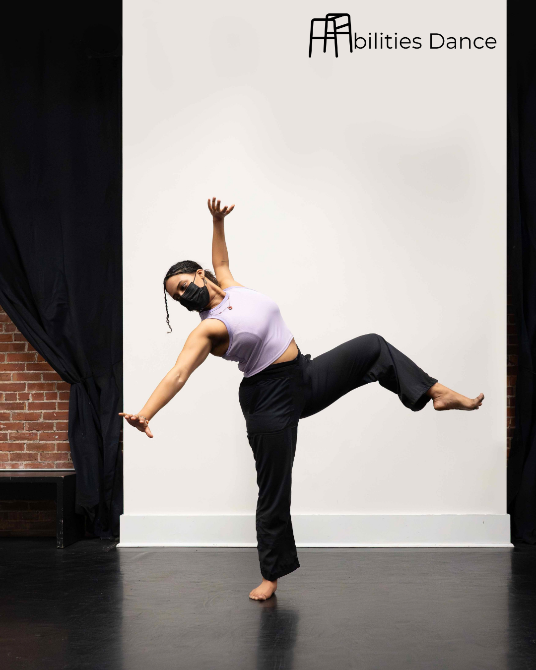 Izzi in a lavender crop top and leggings. One leg raised bent with foot flexted and arms extended on a diagonal with hands reaching