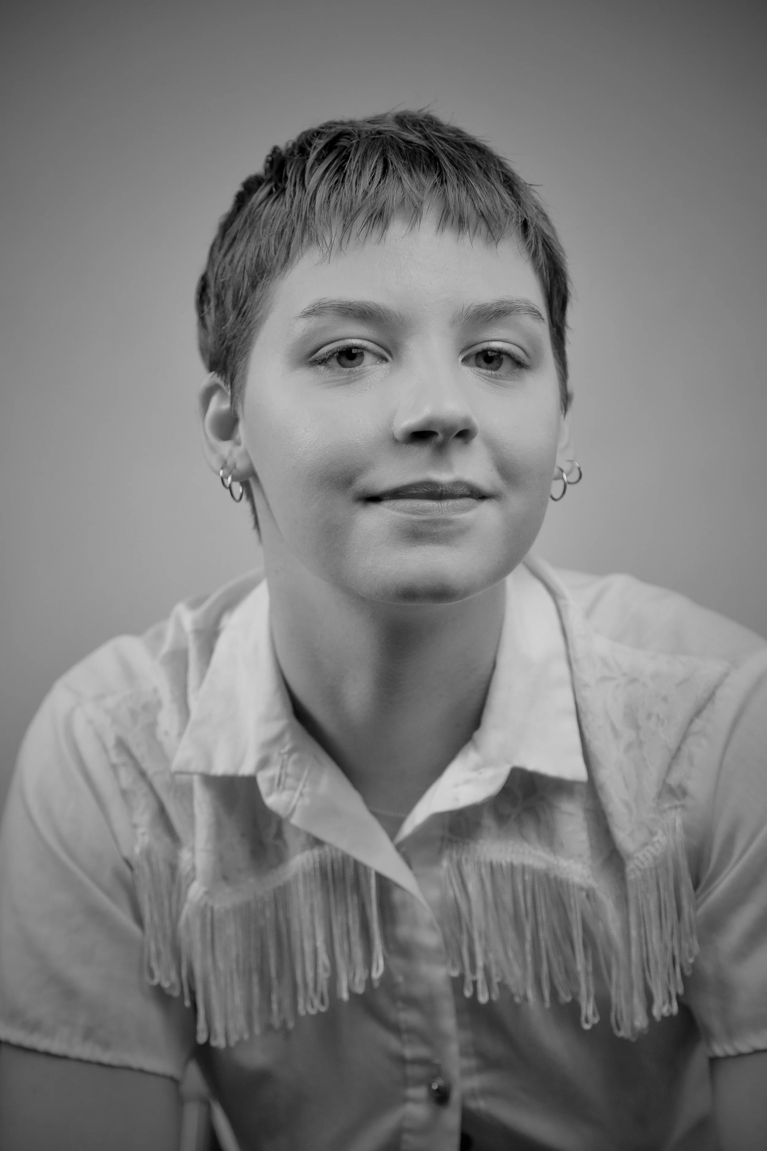 Black and white image of Ava slightly smiling to camera in a headshot.