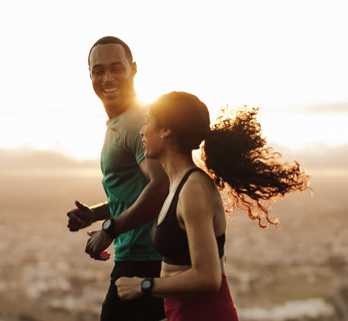 A couple jogs together at sunrise, smiling as they enjoy an outdoor workout, representing vitality, energy, and a healthy, active lifestyle.