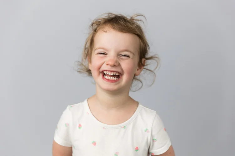Child laughing against a light gray backdrop