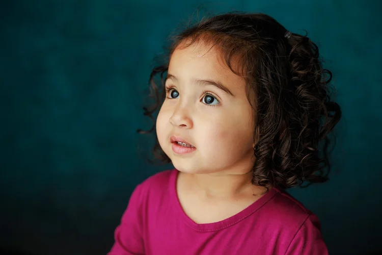 Child looking to the side against a teal backdrop