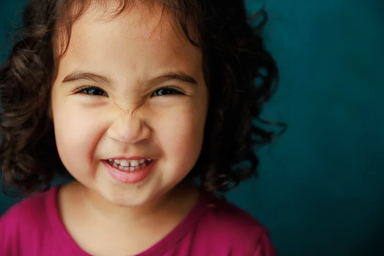 Child laughing against a teal backdrop