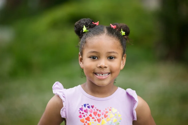 Child smiling outdoors with a softly blurred background