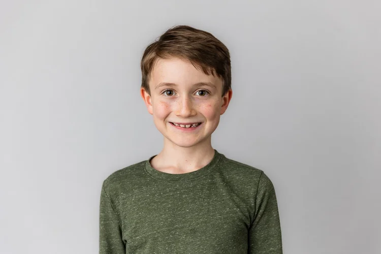 Student smiling in a green shirt against a light gray backdrop