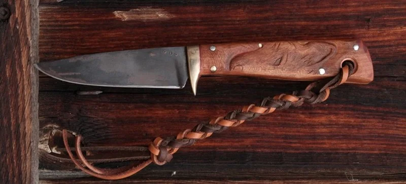 a carved wolf head, a custom handmade hand forged hunting knife