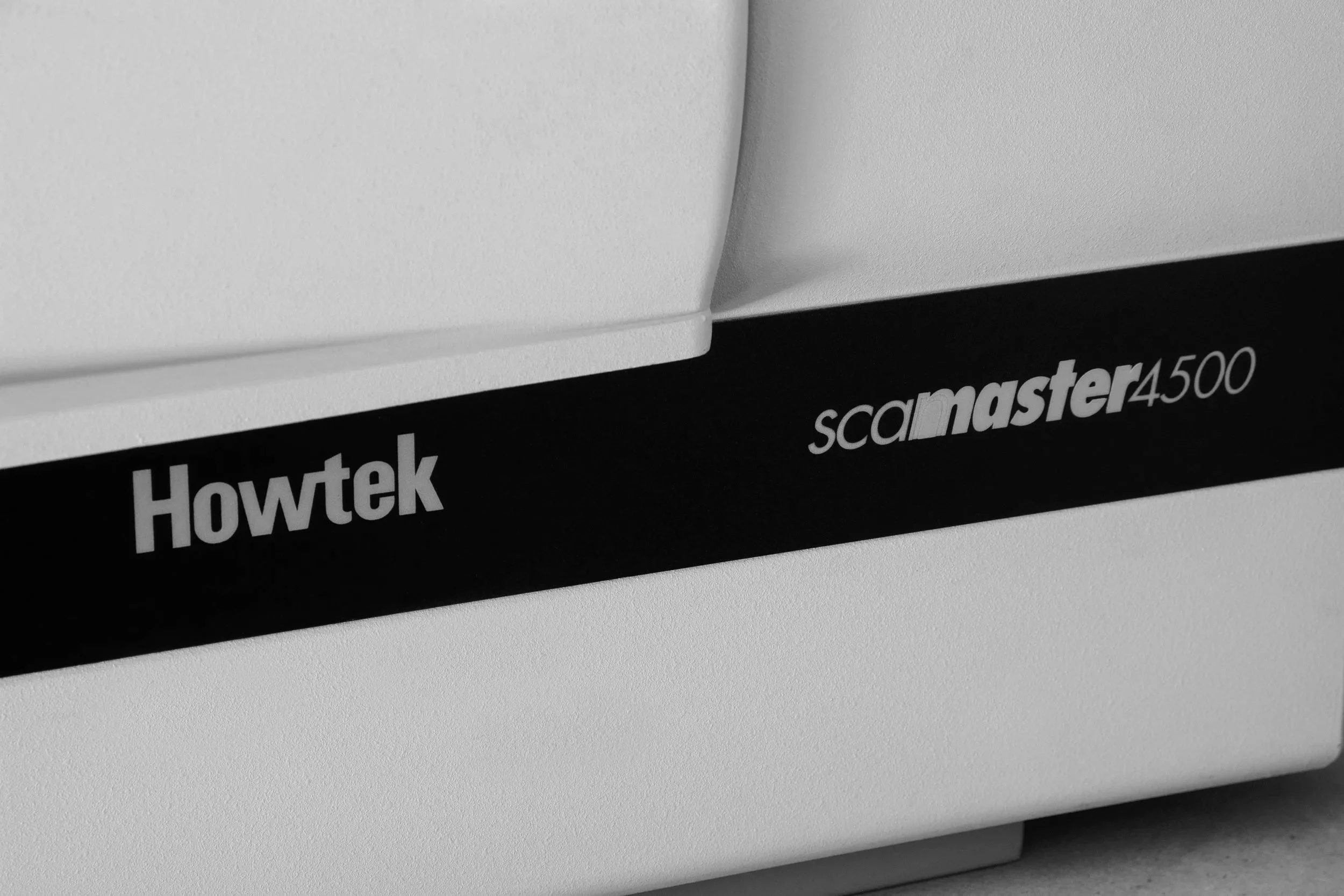 Close-up of a white Howtek ScanMaster 4500 scanner with black branding and model number on the side.