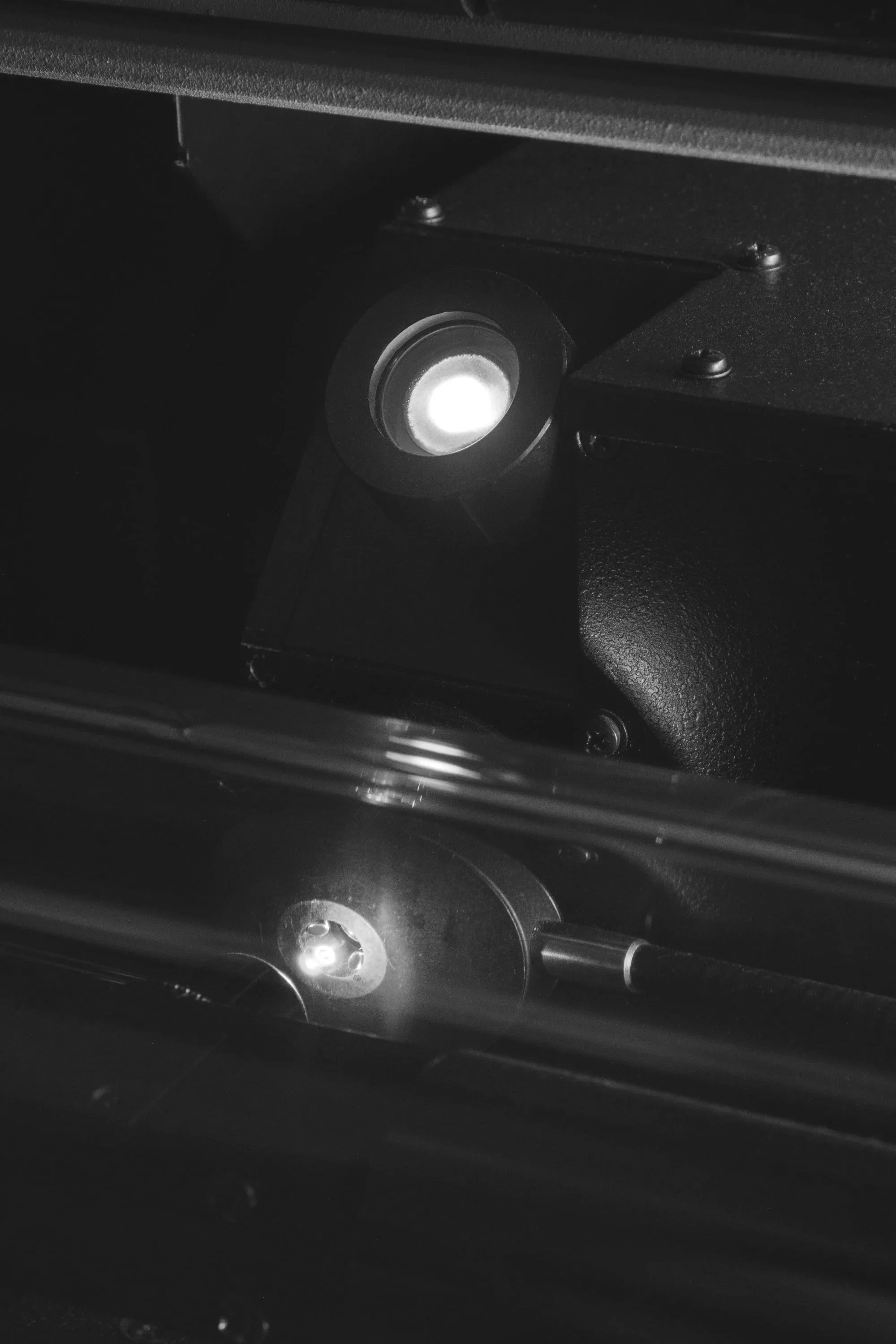 Close-up of a mechanical or technical device with a prominent circular element emitting light, within a dark setting.
