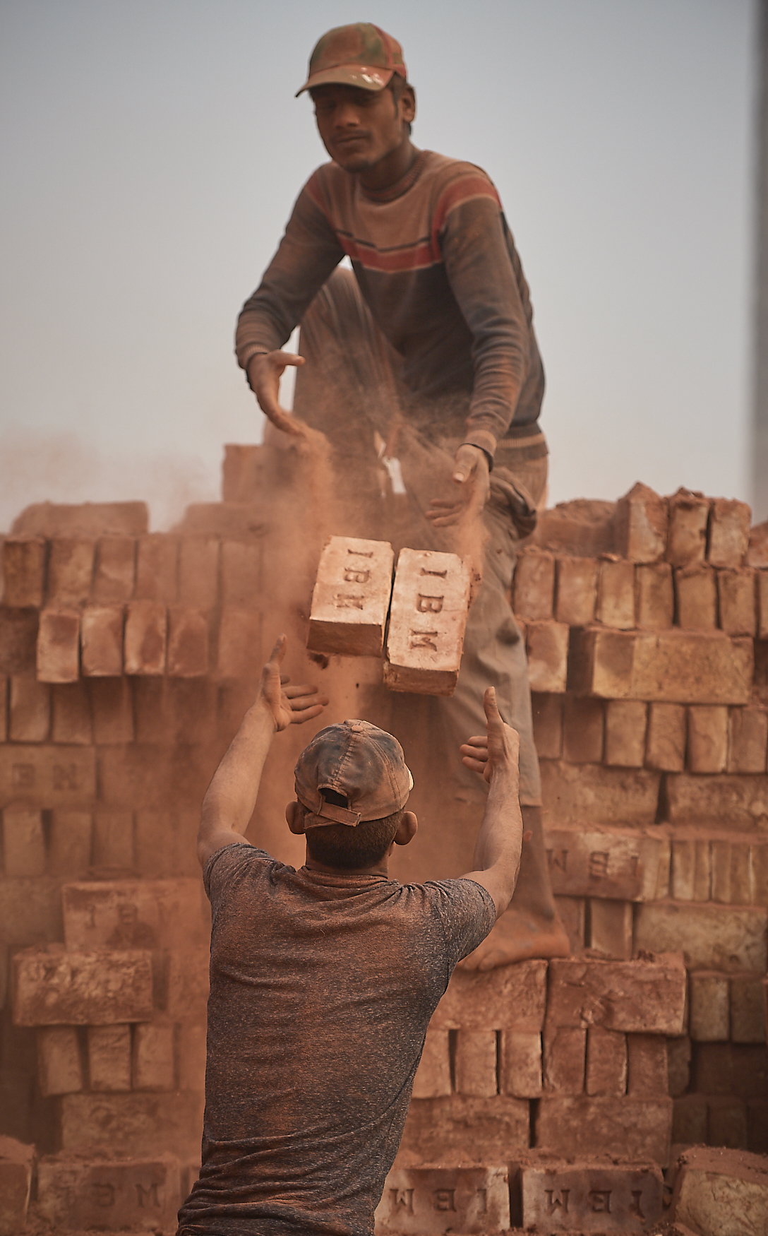 workers stacking dry bricks for baking